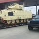 A tank sits next to a junker on a flatbed.
